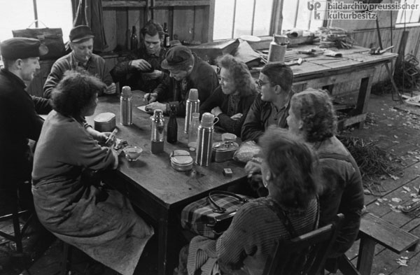 Die Mitglieder einer „sozialistischen Arbeitsgemeinschaft” bei der Mittagspause in der Baracke einer Baustelle in Potsdam (1959)